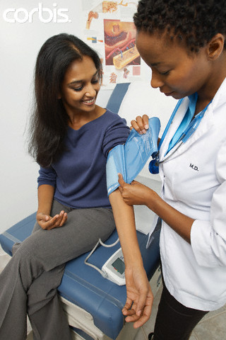Médica medindo a presão arterial de mulher