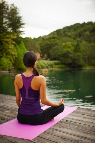 mulher praticando yoga em frente a lago