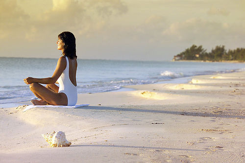 Mulher meditando na praia Meditacao encontre o seu estado zen