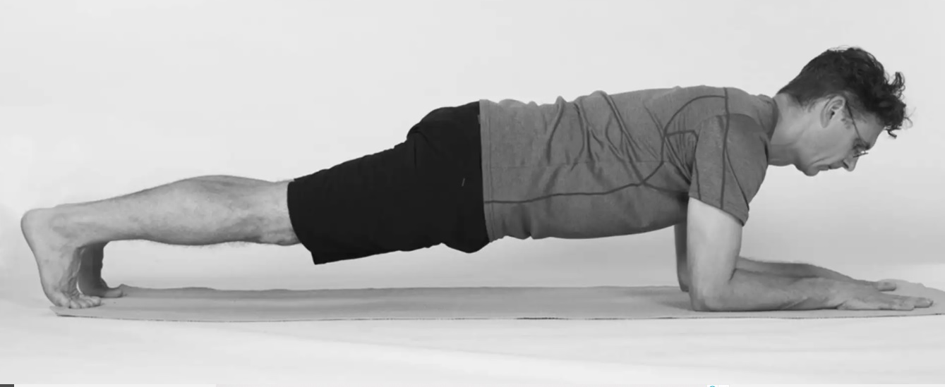 homem idoso fazendo a prancha baixa em tapete de Yoga, com óculos e foto preto e branco