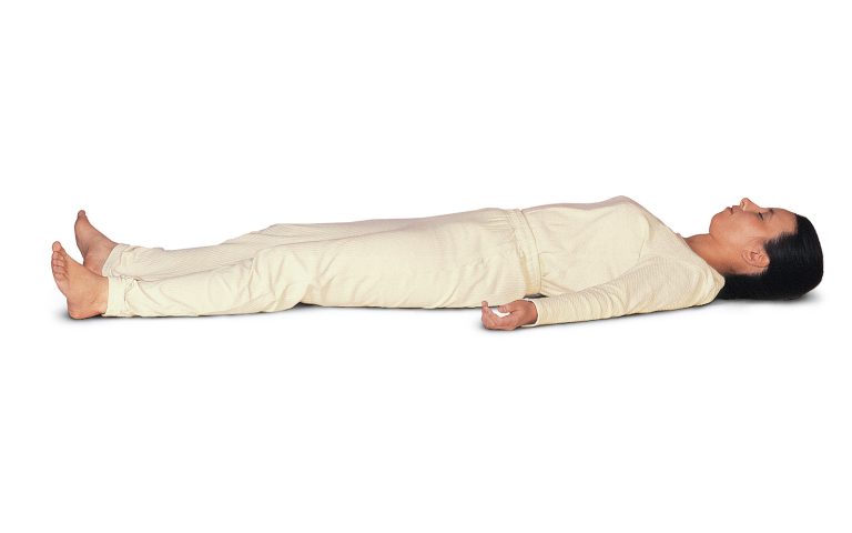 mulher de calça e blusa brancos deitada em fundo infinito branco, de barriga para cima, cabelos escuros e presos, relaxando no solo