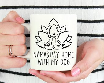 caneca branca com desenho de cachorro com pernas cruzadas a mãos sobre os joelhos em frente a uma flor de lotus com a inscrição: Namast'ay home with my dog