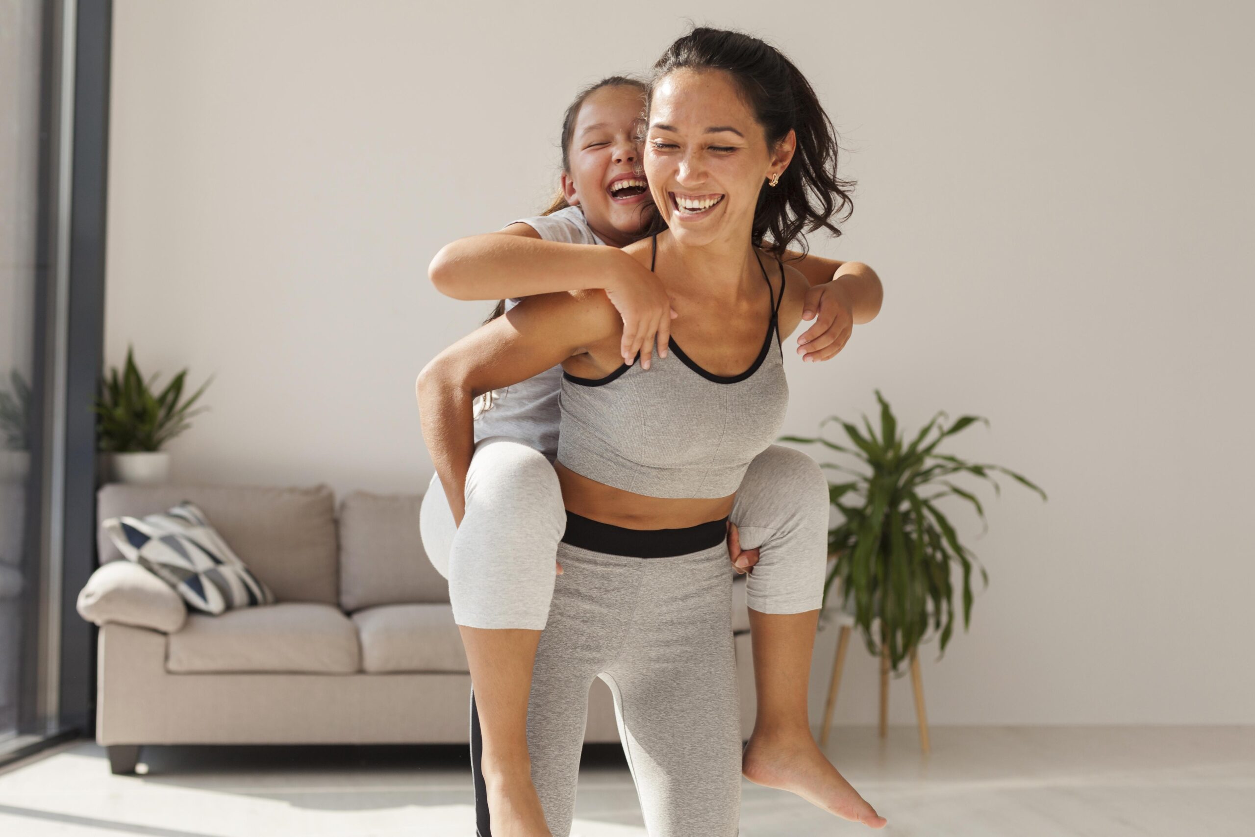 Mãe e filha felizes, praticando Yoga em casa. Saiba os benefícios do Yoga para a saúde das mães