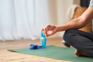 Jovem sentado no tapete de yoga e meditando. São inúmeros os benefícios da prática do Yoga para diabéticos