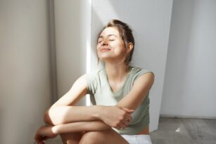 Mulher tomando sol e se acolhendo em postura de autocuidado