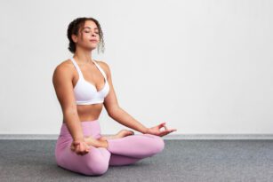 Mulher praticando uma postura simples de yoga, representando a prática acessível de yoga para iniciantes.