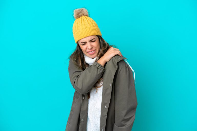 Pessoa sentindo dores nas articulações durante o frio com umas das mãos sobre o ombro
