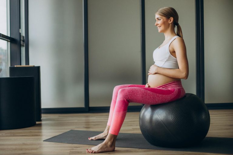 Mulher fazendo exercício de pilates para gestantes sobre bola suíça